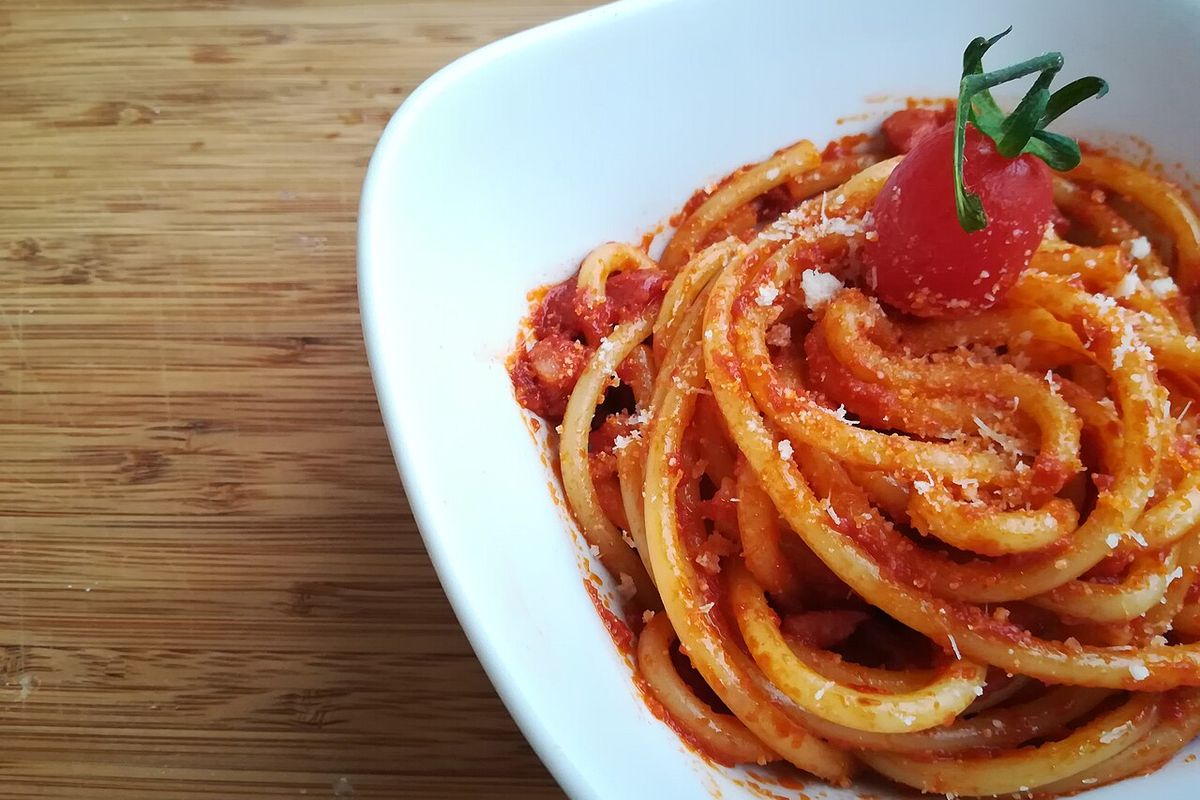 Bucatini all'amatriciana servido em tigela branca