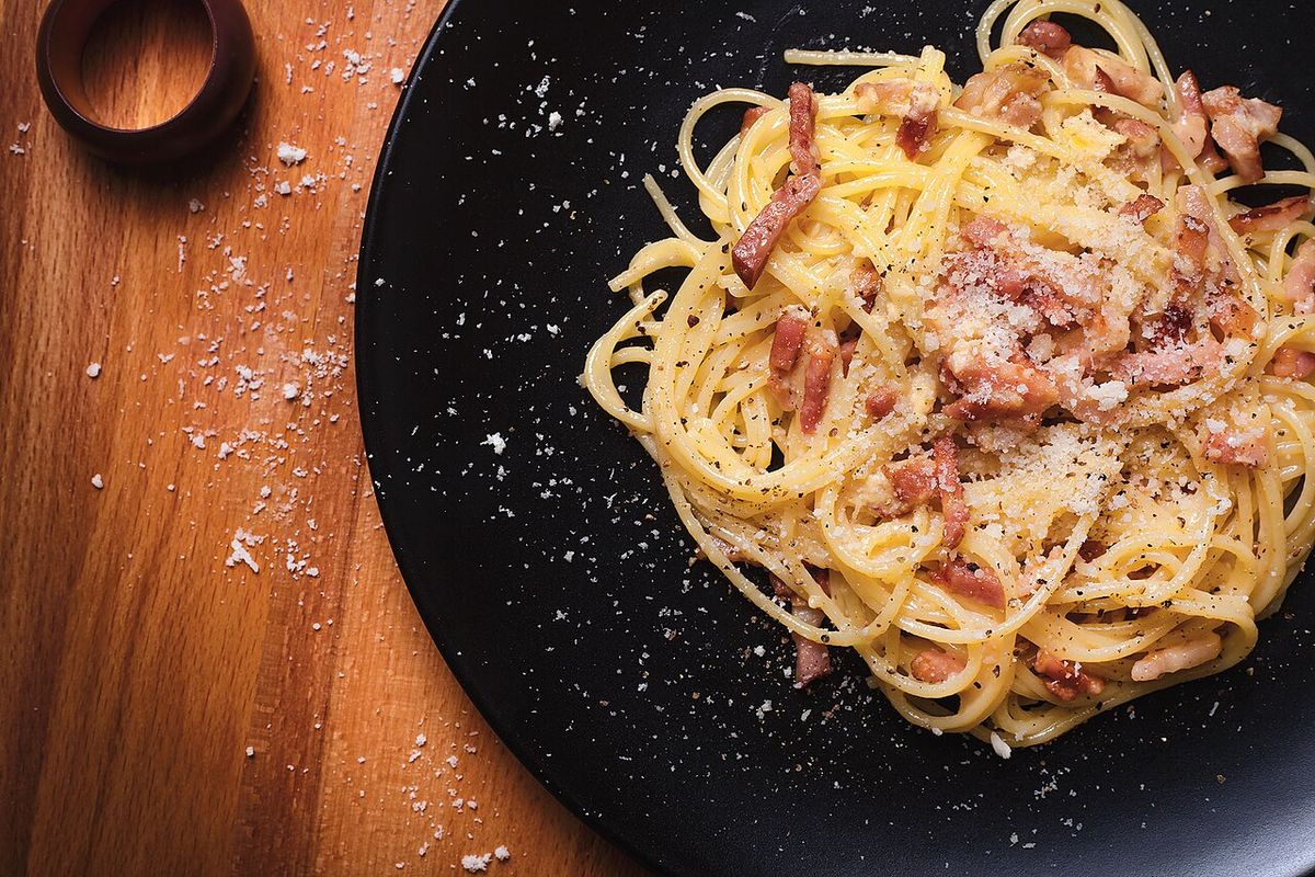 Espaguete à carbonara com guanciale e pecorino em prato escuro